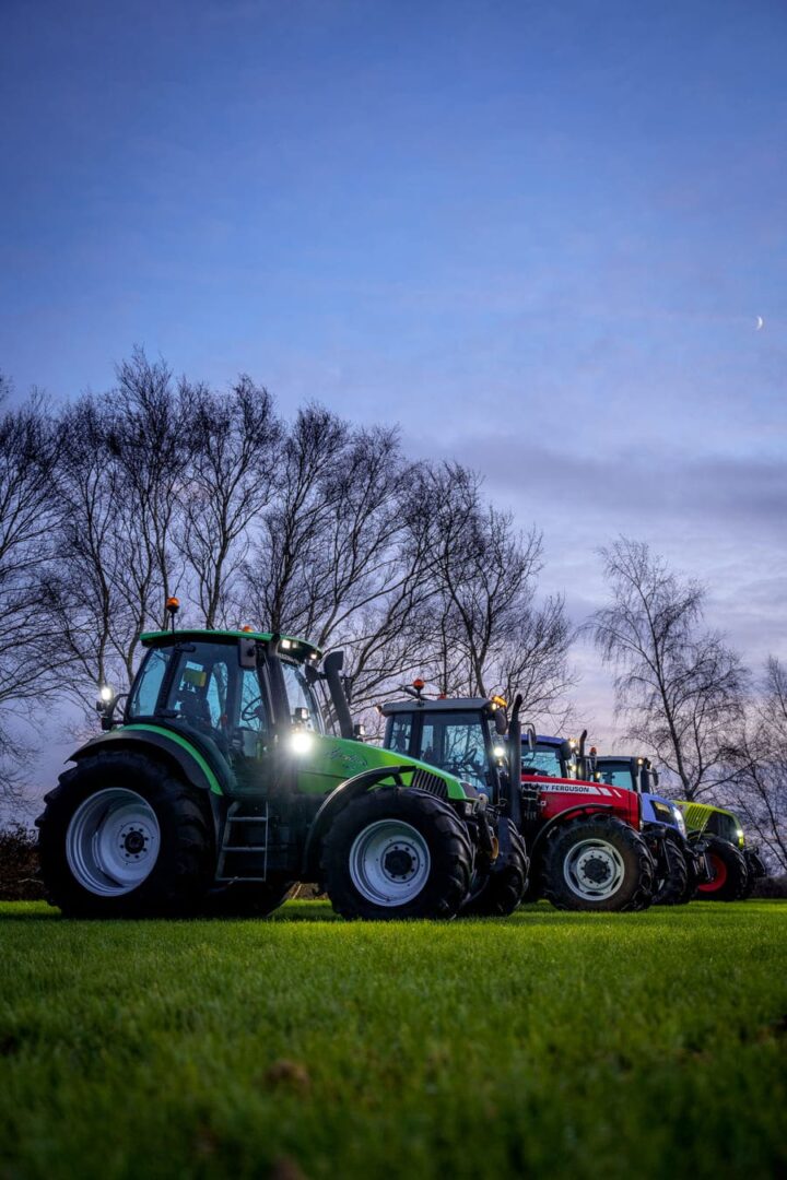 Ciągniki z włączonymi światłami LED na polu o zmierzchu